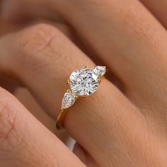 a woman's hand with a diamond ring on top of her finger and an engagement band