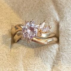 a gold ring with two diamonds on it sitting on top of a white cloth covered surface