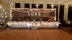 a decorated dance floor with string lights and love sign on the wall behind it at a wedding reception