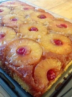 a pineapple upside down cake sitting on top of a cooling rack next to a wooden table