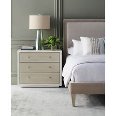 a white bed sitting next to a night stand with two lamps on top of it