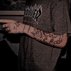 a man with tattoos on his arm pointing at something