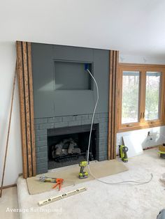 a fireplace being built in a living room with tools on the floor next to it