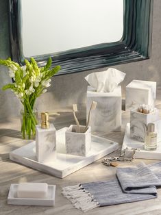 marbled bathroom accessories including soap, toothbrushes and flowers in front of a mirror