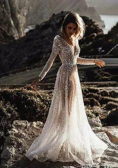 a woman standing on top of a rocky hillside wearing a dress with sequins