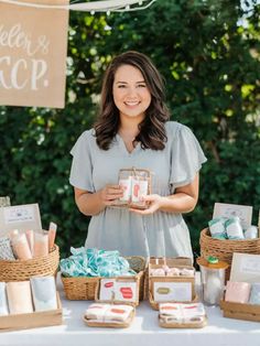 a woman standing in front of a table filled with items