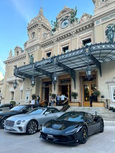 three luxury sports cars parked in front of a building with people standing outside the entrance