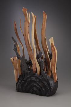 a sculpture made out of driftwood and other wood pieces on a gray background with an animal in the center