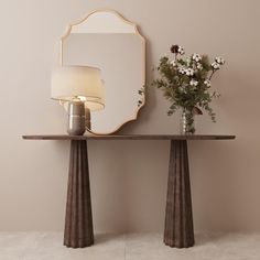 a vase with flowers sitting on top of a table next to a mirror and lamp