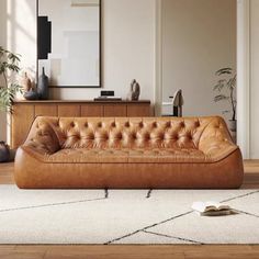 a brown leather couch sitting on top of a wooden floor next to a white rug