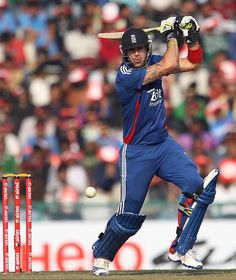 a cricket player hitting the ball with his bat in front of him and spectators watching