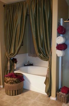 a bath tub sitting next to a window covered in green drapes and red roses