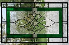 a green stained glass window with trees in the background