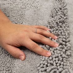 a person's hand on top of a gray rug