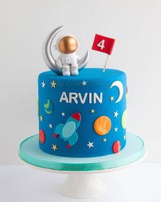 a blue cake with an astronaut on top and the number four on it's side