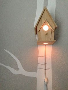 a small bird house on the wall with a light coming out from it's side