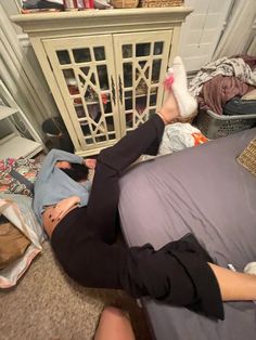 a woman laying on the floor with her feet up in front of a bookcase