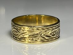 "Lovely antique wide gold band in solid 18K yellow gold. This beautiful antique ring measures 6.2mm north to south and is hand engraved on the outside with what appears to be a hand tooled floral theme. The band has a lovely patina and is in excellent condition. The age of this band is unknown. Ring size 5 1/4 and easily sized up or down several sizes. All hallmarks and patterns carefully preserved during sizing or restoration. Please allow three business days for sizing. One month layaway payme Traditional Etched Yellow Gold Engraved Ring, Traditional Yellow Gold Engraved Ring, Victorian Gold Engraved Ring With Decorative Band, Victorian Gold Engraved Etched Ring, Victorian Gold Etched Engraved Ring, Ceremonial Gold Engraved Ring, Victorian Etched Gold Engraved Ring, Gold Engraved Wide Band Ring Hallmarked, Gold Engraved Ring With Hallmarked Wide Band