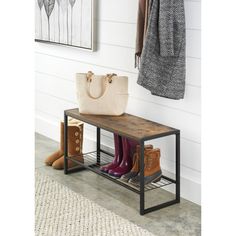 a wooden bench with two boots and a purse on it next to a coat rack