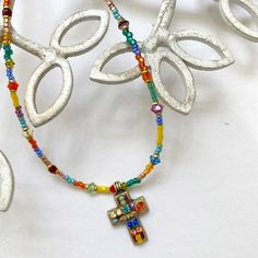 Decorated by hand with Swarovski crystals and glass beads, this cross necklace is bursting with color and life. This piece will make a lovely addition to your spring wardrobe. -Materials: Swarovski crystals, glass beads -Metal: 24K gold electroplated over brass -Size: Chain adjustable 14-18″, 1/2″ pendant -Lobster claw clasp -Handmade in our NYC studio -Complimentary gift wrapping -Item #: N1118 Repairs Policy: Repairs are free. Customers will only be asked to pay $5 for shipping. Expect process Spiritual Beaded Cross Pendant Necklace, Bohemian Cross Beaded Necklace Gift, Handmade Multicolor Cross Necklace, Beaded Spiritual Cross Pendant Necklace, Multicolor Beaded Cross Jewelry, Spiritual Multicolor Cross Necklace, Beaded Crucifix Necklace, Beaded Cross Pendant Necklace As A Gift, Bright Crystal