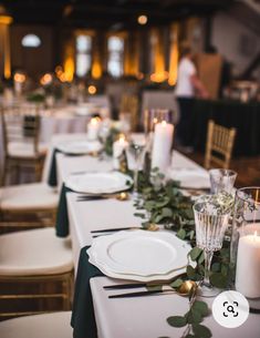 the table is set with candles, plates and greenery for an elegant wedding reception