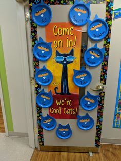 a classroom door decorated with blue cat magnets and the words, come on in we're cool cats