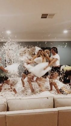 a group of people standing on top of a couch covered in white powder and confetti