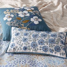 two blue and white pillows sitting on top of a bed