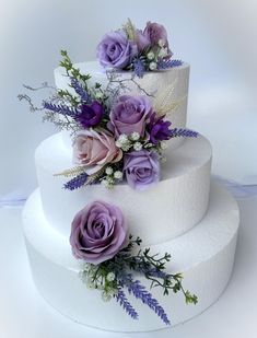 three tiered white cake with purple flowers on top