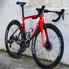 a red and black bike leaning against a white wall with the words cannon written on it