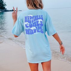 "Experience the essence of carefree living with our \"Happiness Comes In Waves\" Comfort Colors Oversized Beach Tee. Crafted for the trendy and free-spirited woman, this shirt features a captivating wave design on the front, symbolizing life's ebbs and flows. Made from premium Comfort Colors fabric, renowned for its softness and durability, this shirt is perfect for beach days, lake trips, and cruises. Its vintage boho charm adds a timeless touch, while the Y2K-inspired design speaks to modern t Oversized Summer Beach Shirt, Oversized Summer Tops For Leisure, Oversized Relaxed Tops For Beach Season, Relaxed Oversized Tops For Beach Season, Oversized Graphic Print Beach Shirt, Oversized Graphic Print Shirt For Beach, Oversized Vacation Shirt With Letter Print, Oversized Letter Print Shirt For Vacation, Oversized Graphic Print Vacation Shirt