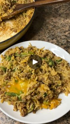 a white plate topped with rice and meat next to a skillet filled with vegetables