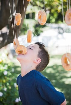 a young boy eating donuts hanging from strings