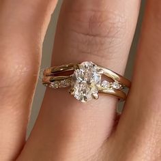 a woman's hand with two gold rings on it and a diamond ring in the middle