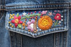 the back pocket of someone's jean jacket with embroidered flowers on it and buttons