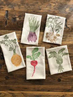 four vegetable printed napkins sitting on top of a wooden table