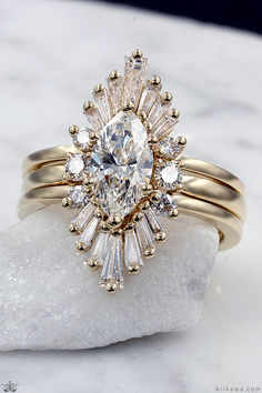 This Art Deco style enhancer wraps your engagement ring in a sunburst of brilliant baguette diamonds or gemstones! Handcrafted to perfectly cradle your engagement ring, this enhancer creates a dynamic halo around the center stone. Your engagement ring slides within this open double band, with the center setting framed in the stones of your choice. A perfect way to upgrade an existing ring or complete a bridal set. Shadow Wedding Band, Marquise Engagement Ring Stack, Wedding Ring Wraps, Engagement Ring Wraps, Unique Wedding Band Sets, Wrap Wedding Band, Diamond Shaped Engagement Ring, Ring Wraps, Radiant Diamond Engagement Rings