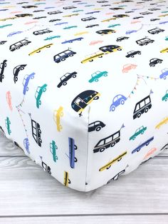 a baby crib sheet with cars and trucks on it, sitting on a wooden floor