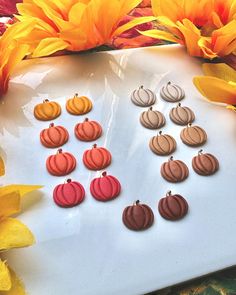 a bunch of earrings sitting on top of a white plate next to flowers and oranges