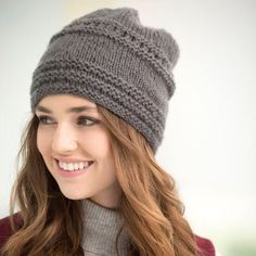 a woman with long hair wearing a gray knitted hat and smiling at the camera