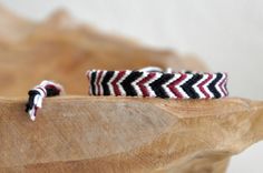 two black and white striped bracelets sitting on top of a wooden table next to a piece of wood