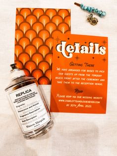 a bottle of defais next to an orange card and necklace on a table