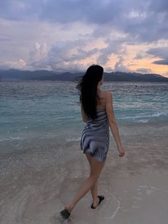 a woman walking on the beach at sunset