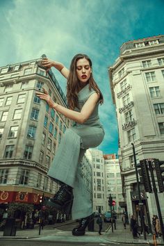 a woman in grey dress standing on top of a building