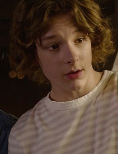 a young man with curly hair wearing a striped shirt