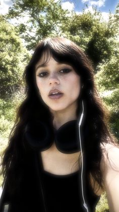 a woman with headphones standing in front of trees