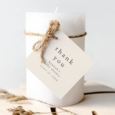 a white candle with a thank you tag on it