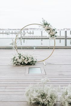 an outdoor ceremony setup with flowers and greenery on the ground, along with a circular arch