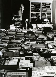 a man sitting at a table covered in books