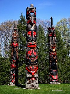 three totems are standing in the grass near trees